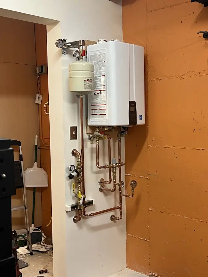Plumbing technician inspecting water heater connections in Licking
